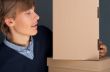 Portrait of young man leaning on box against grey wall. He is st