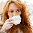 Portrait of beautiful red hair girl drinking coffee on winter ba