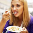Closeup portrait of an attractive young woman eating fruit salad