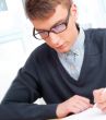 High school - Young male student write notes in classroom
