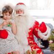 Christmas theme: Santa Claus and little girl having a fun. Indoo