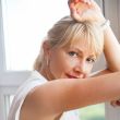 Closeup portrait of smiling woman standing near big window