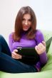 Happy young pretty woman at home, smiling and using her tablet c