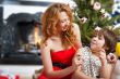 Mother and her daughter sitting together near christmas tree