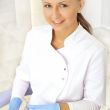 woman dentist at her office smiling wearing formal medical suit