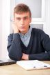 Young student man working in bright room, sitting at desk, using