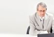 Portrait of an older businessman with a computer and a cup.
