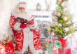 Santa sitting at the Christmas tree, near fireplace and reading 