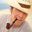 Closeup of a happy brutal young man looking at camera and smokin