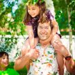 Artistic lifestyle photo of happy family: father piggyback his d