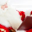 Santa sitting at home and reading a book. Indoors