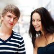 Portrait of young couple embracing at shopping mall and looking 