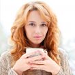 Portrait of beautiful red hair girl drinking coffee on winter ba