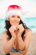 Young beautiful woman wearing christmas hat showing heart shape 