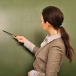 Portrait of young woman teacher standing near blackboard and exp