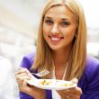Closeup portrait of an attractive young woman eating fruit salad