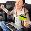 Portrait of a young woman lying on the couch and shopping from t