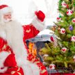Santa sitting at the Christmas tree, near fireplace and looking 