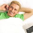 A man in his bed speaking cell phone and looking away