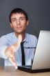 Businessman gives a handshake. Sitting near his laptop at his de