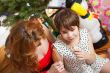 Mother and her daughter sitting together near christmas tree. To