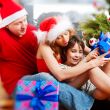 Young happy familye near a Christmas tree at home holding gift a