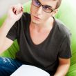Young adult man writing in his copybook while sitting on a large