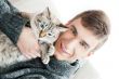 Relaxed man sitting on armchair holding and petting pet cat