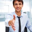 Businessman gives a handshake. Sitting near his laptop at his de