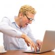 Portrait of funny man screaming during typing a document on his 