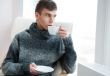Portrait of a young man drinking coffee while sitting on armchai