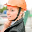 Young architect-woman wearing a protective helmet standing on th