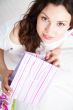 Portrait of young beautiful awake woman with gifts on bed at bed