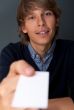 Business man handing a blank business card over grey background