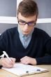 High school - Young male student write notes in classroom