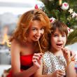 Mother and her daughter sitting together near christmas tree