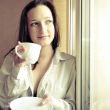Portrait of cosy young girl standing near a window at home
