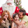 Happy family embracing and sitting on the floor in front of Chri