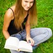 Beautiful female student outdoors with a book at campus park