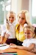 Young pretty teacher helping her little students in classroom