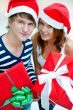 Young happy couple in Christmas hats standing together and holdi