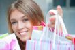 Shopping woman with lots of bags smiles inside mall. She is happ