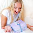 Bedroom surprise present - young happy woman in bedroom