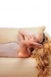 Young Girl enjoys listening music in headphones lying on sofa