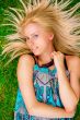 Young woman laying on green grass with hair like a sun around he
