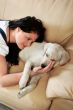 Young woman with dog sitting on sofa