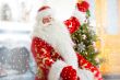 Santa sitting at the Christmas tree, near fireplace and looking 