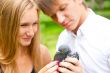 Portrait of young handsome couple holding a dove in park