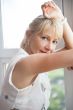 Closeup portrait of smiling woman standing near big window