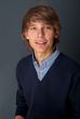 Portrait of young relaxed business man leaning on grey wall look